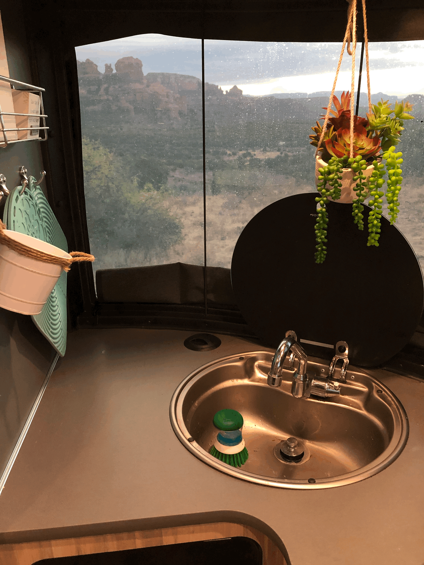 Enjoy the scenic red rock view from your RV rental! This cozy kitchen features a sink, hot pads, and decorative succulents.