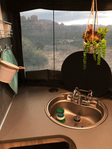 Enjoy the scenic red rock view from your RV rental! This cozy kitchen features a sink, hot pads, and decorative succulents.