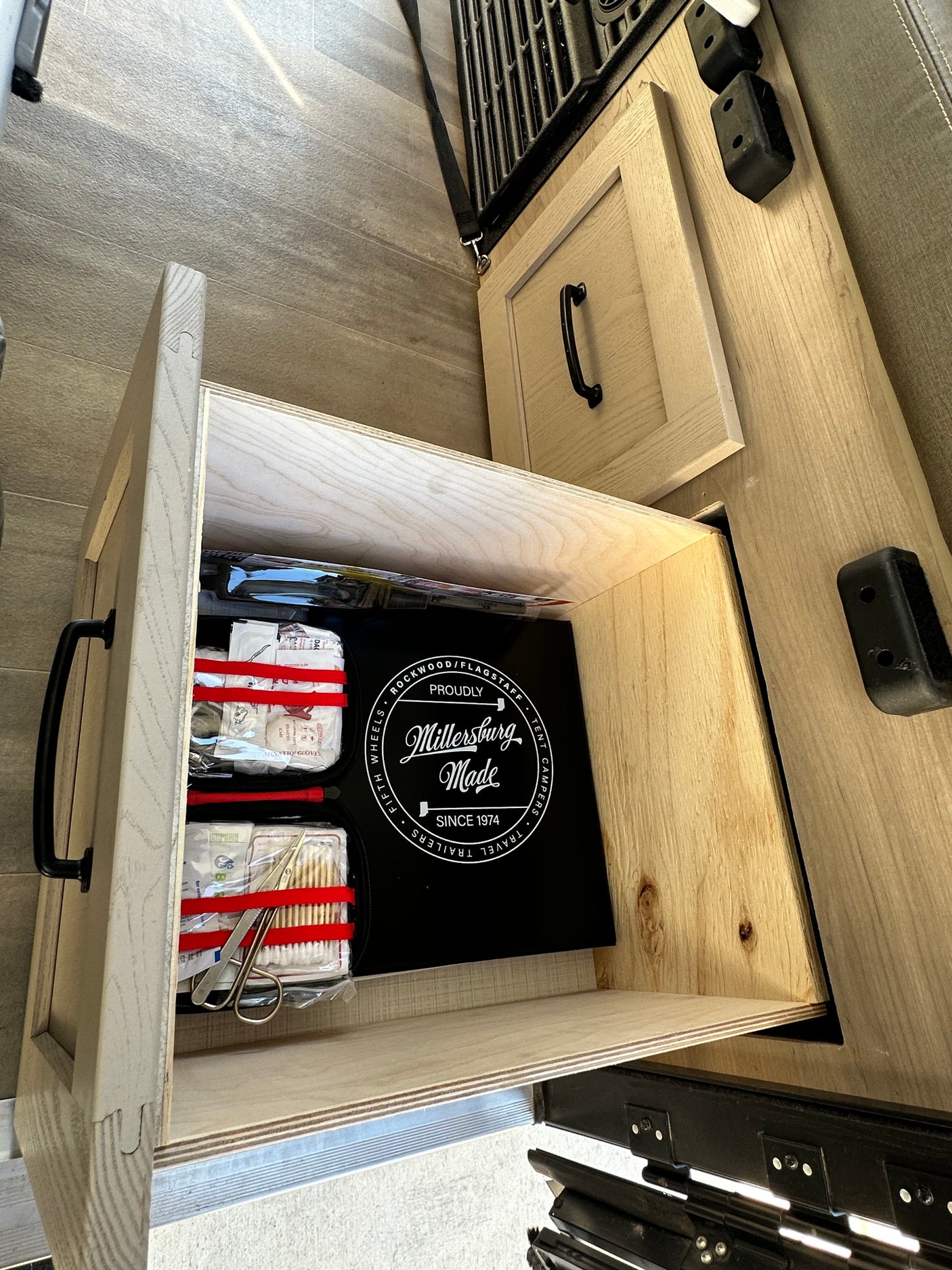 Open drawer in an RV rental, revealing a "Millersburg Made" kit with first-aid supplies. Essential for camper or travel trailer adventures.