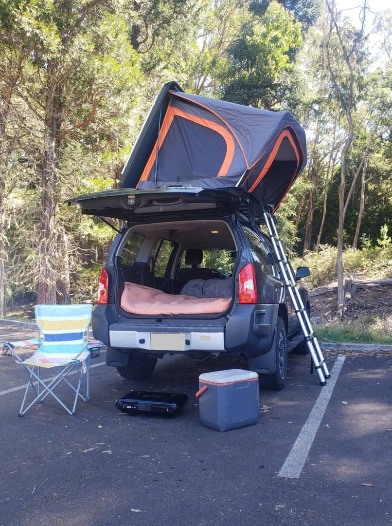 This car camping setup with a roof top tent, ladder, and gear like a cooler/stove, offers an rv rental alternative.