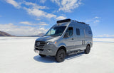 This grey Mercedes Sprinter van rv rental on vast salt flats under blue skies is perfect for your next off-road adventure trip.