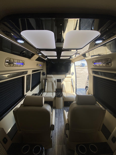 Spacious luxury RV rental interior with individual captain's chairs, large entertainment screen, and ambient lighting.