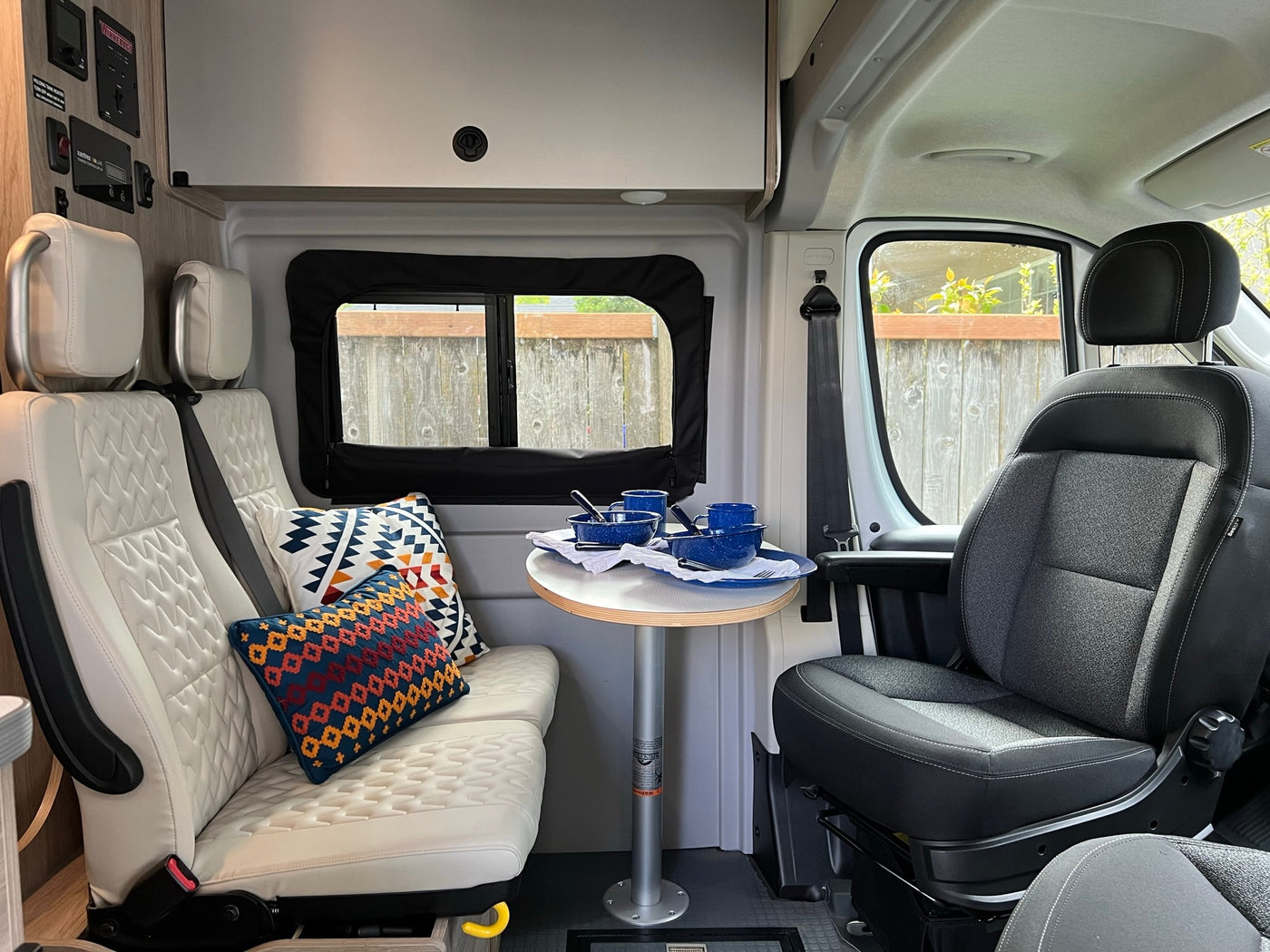  facing a majestic mesa under blue skies.|RV rental interior: cozy camper van dining area with white quilted seating — photo 3