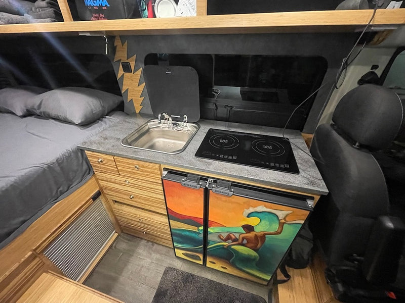  with ocean waves.|Inside a modern RV rental: view from the rear showing kitchen counter with sink & induction cooktop — photo 8
