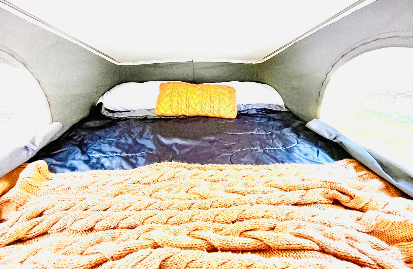  and scenic window views.|Comfortable RV rental bed setup with a knitted blanket — photo 2