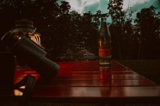 Dark wooden table with telescope & lantern. RV rental units parked in distance, signaling a relaxing outdoor evening.