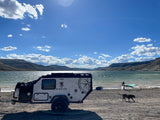 Overlanding RV rental by a lake, offering adventure with watersports, scenic mountains & a playful dog.