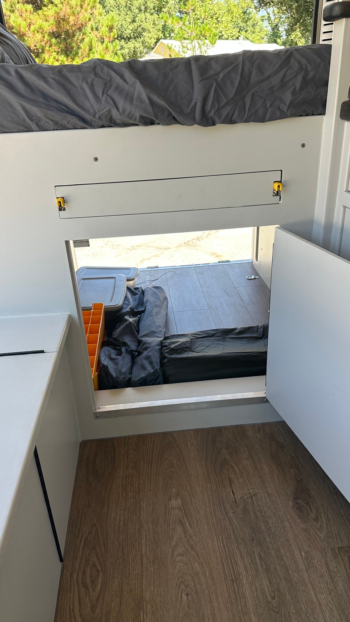  and storage. View from the open side door.|A comfortable bed with dark gray bedding and integrated charging ports inside a bright RV rental. Scenic outdoor view.|Interior of an rv rental: a grey bed on left — photo 14