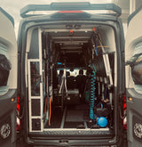 Inside a custom RV rental: Organized mobile setup with bike rack, air compressor, & gear storage.