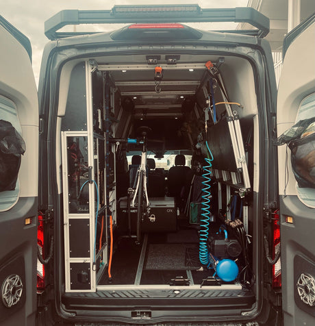 Inside a custom RV rental: Organized mobile setup with bike rack, air compressor, & gear storage.