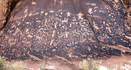 Ancient petroglyphs carved into a dark rock wall, a historical stop on your next RV rental adventure.