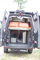Explore the comfortable interior of this camper van RV rental, featuring a cozy bed & ample storage. Perfect for your next adventure.