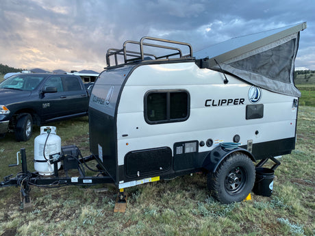 This Clipper pop-top travel trailer rv rental is ready for outdoor adventure, parked under a cloudy sky.