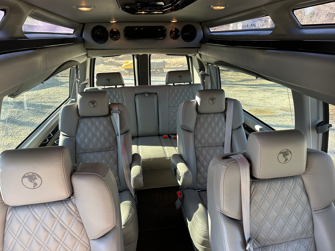 Inside a premium RV rental: light grey quilted leather captain's chairs with unique globe headrests.