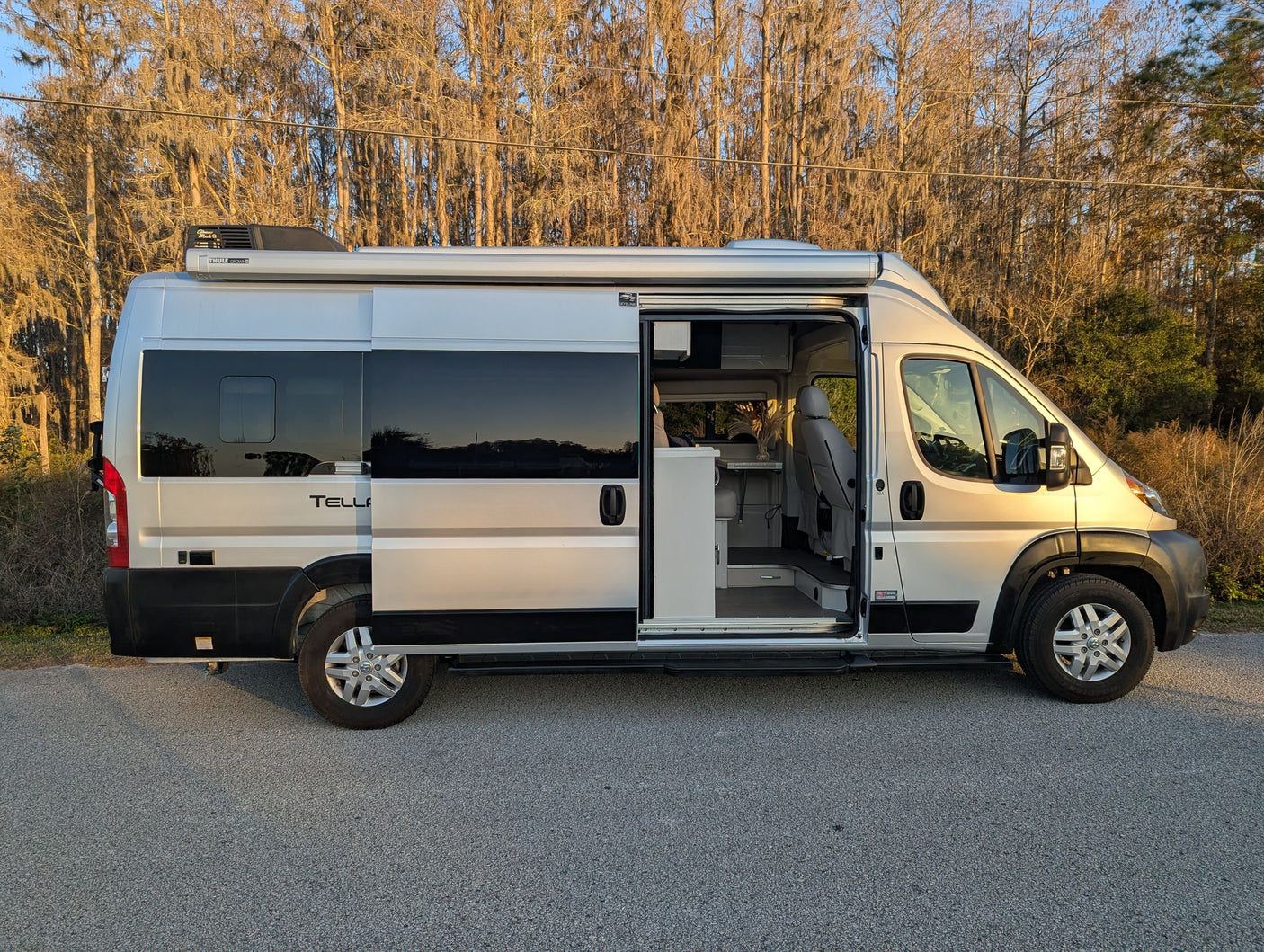 This silver camper van, an ideal RV rental, is parked with its side door open, ready for your next adventure.