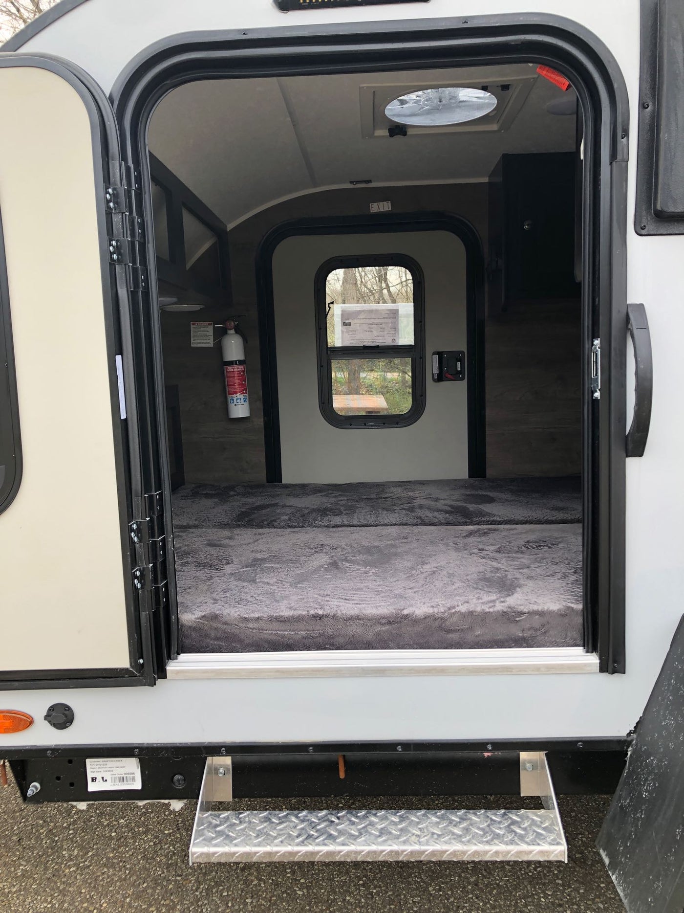 An open door shows the inviting interior of an RV rental, featuring a comfortable bed, fire extinguisher, and overhead vent. — photo 3
