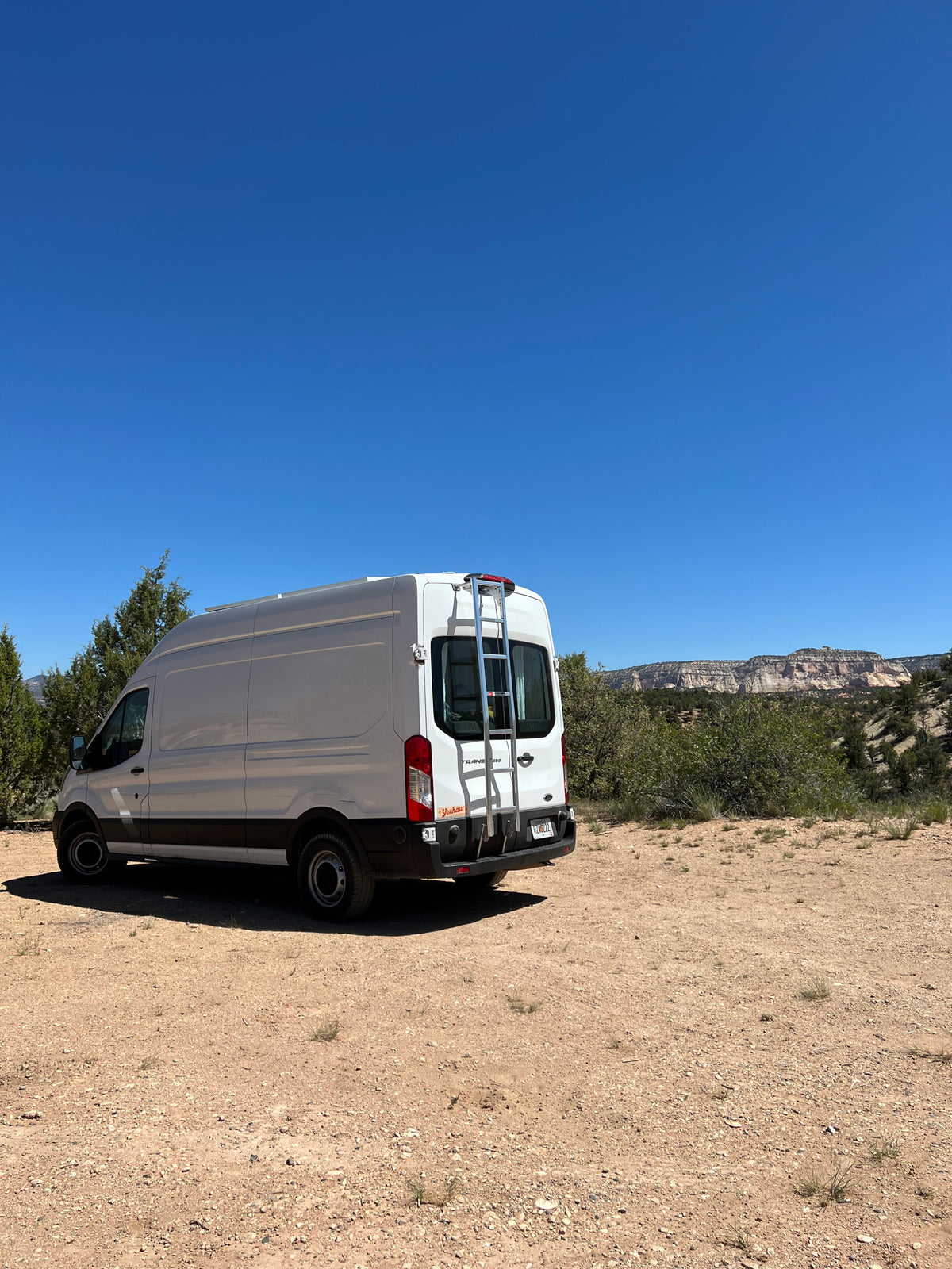 This white Ford Transit **RV rental** is ready for adventure, parked on a dirt road with majestic desert mountains. — photo 6