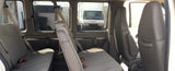 Inside a spacious RV rental van, showing rows of grey passenger seats. Outside, a white truck and industrial area are visible.