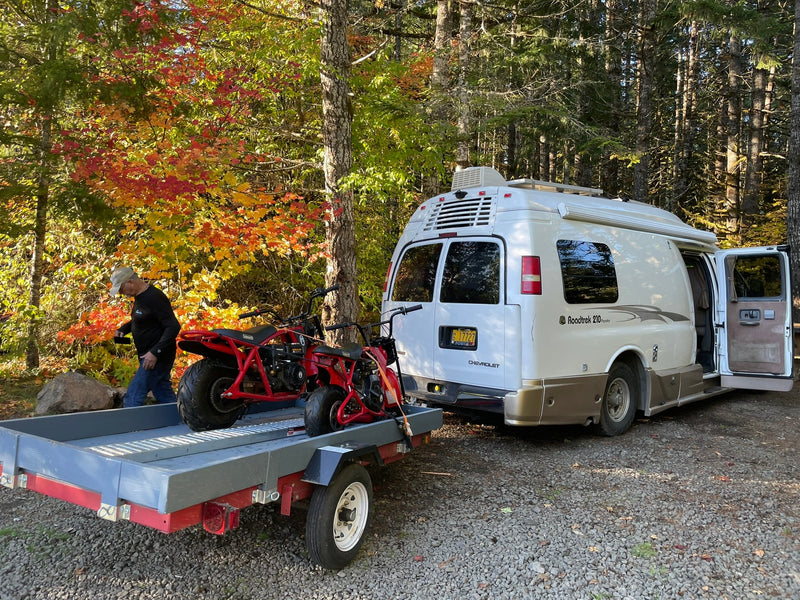  and bed layout.|Relaxing RV rental setup: a Roadtrek camper van with awning extended at a green forest campsite with a picnic table.|A white and tan RV rental is parked in a sunny — photo 7