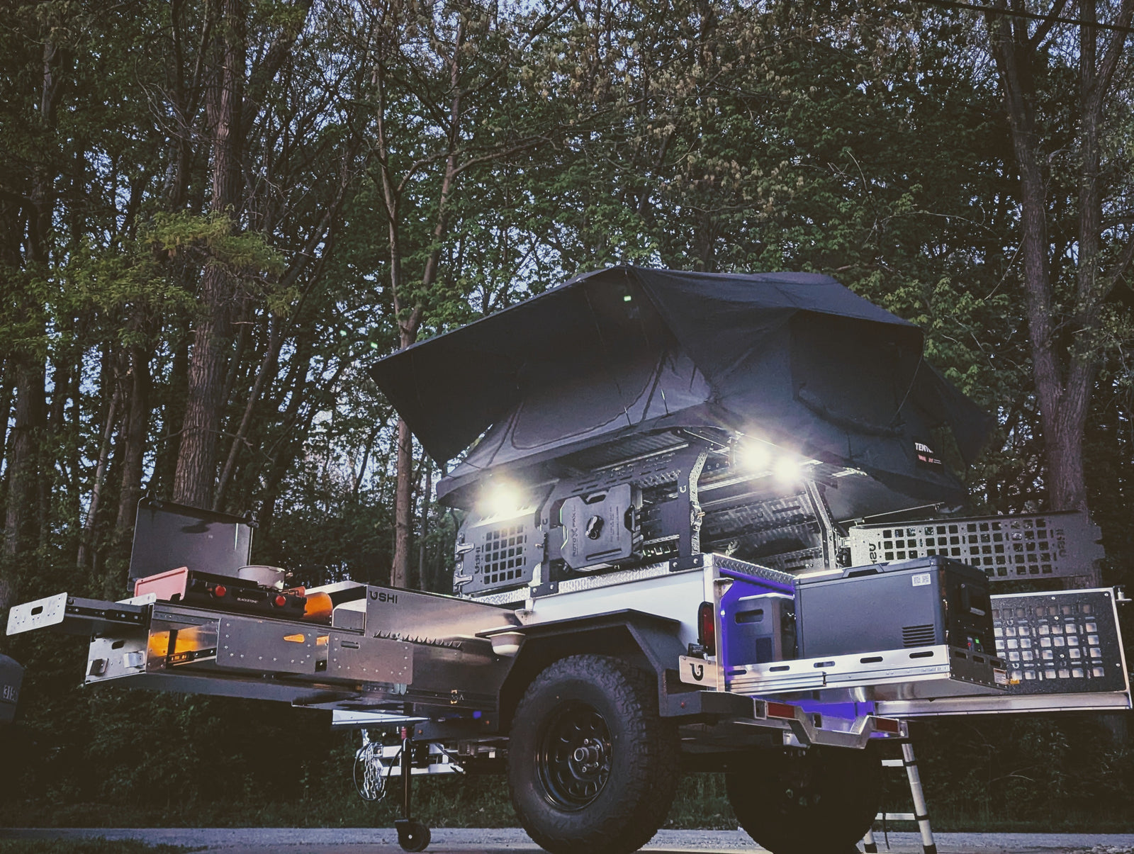Equipped overland camping trailer: rooftop tent, pull-out kitchen, fridge. Ideal for your next RV rental adventure.