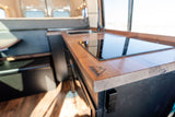 RV rental van's 46 NORTH LONG kitchen: sleek wooden countertop, induction cooktop & sink. Compact living on the go.