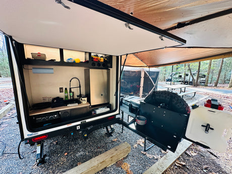 Camping with this compact RV rental! Enjoy the outdoor kitchen, sink, fridge, and shaded awning at your campsite.