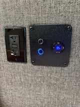 RV rental: Close-up of a wall-mounted AC power outlet and a 13.5V DC USB charging station with 65W/QC 3.0 display.