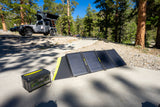 Off-grid RV rental setup: Goal Zero solar panel charges a Yeti power station next to a Jeep with a rooftop tent at a campsite.