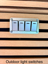 Modern outdoor light switches, brushed metal on a wood slat wall, for convenient exterior lighting in an RV rental.