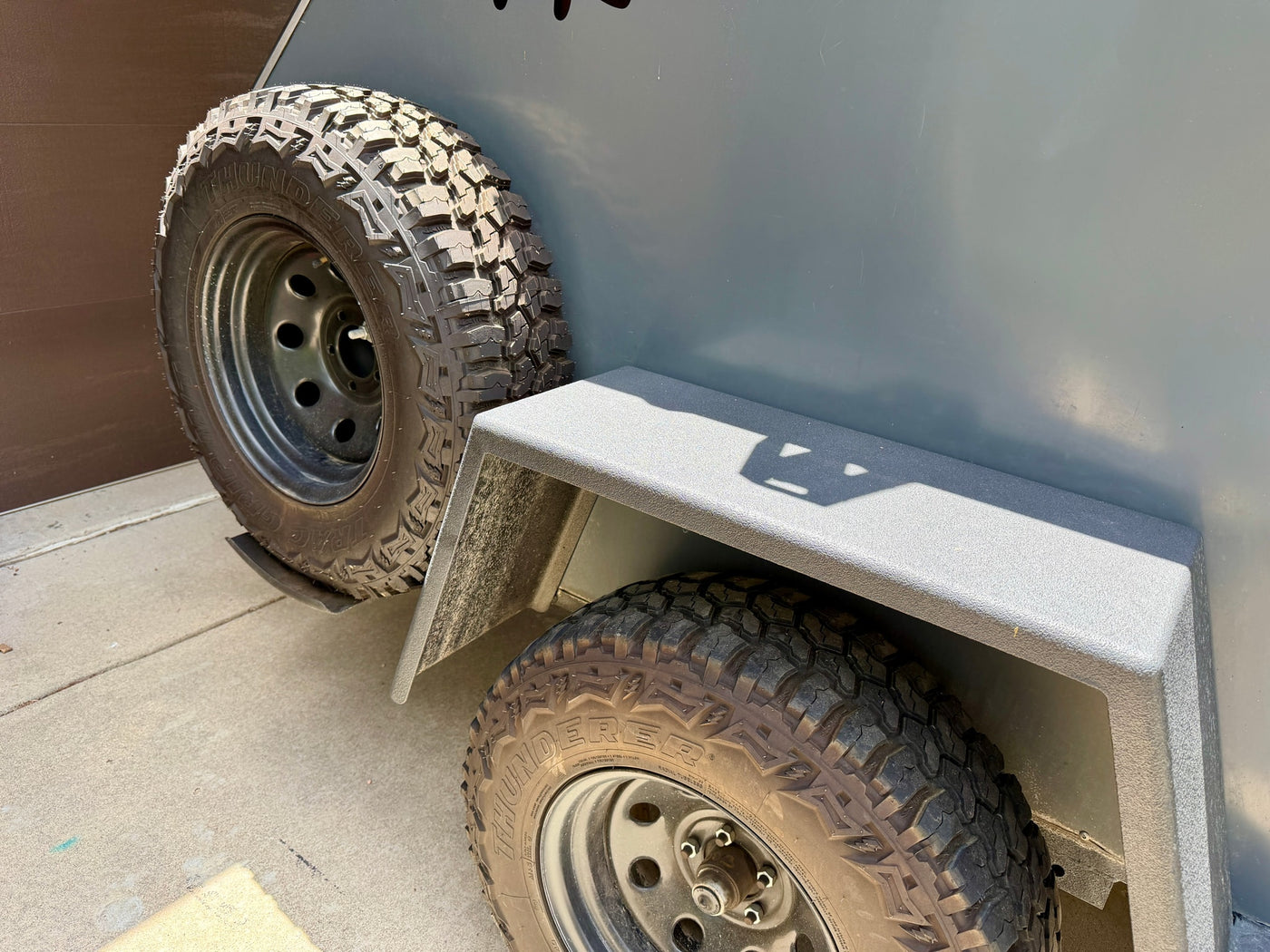 Chunky off-road tires on a grey RV rental trailer. A spare is mounted on the side, ready for adventure. — photo 8