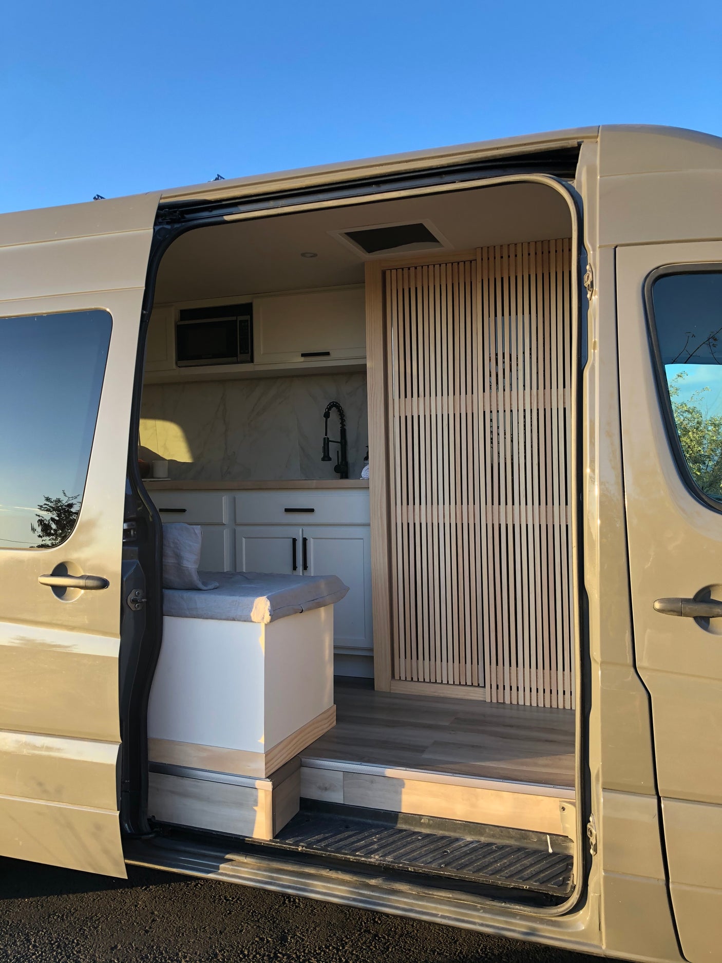 Explore this modern RV rental! Featuring a compact kitchen, built-in seating, and stylish wood details for your next adventure.