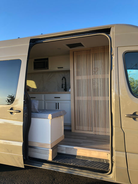 Explore this modern RV rental! Featuring a compact kitchen, built-in seating, and stylish wood details for your next adventure.