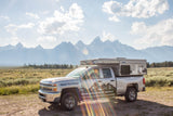 Sunny Teton scene: A Teton Backcountry Rentals truck camper, an RV rental, awaits your adventure with mountains beyond.