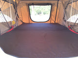 An inviting RV rental rooftop tent interior with comfortable sleeping pad and clear window view for your camping trip.