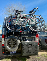 RV rental with 1UP bike rack holding two road bikes, rear spare tire, and Noovo storage box. Adventure-ready van.