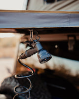 Outdoor shower setup for an rv rental: a multi-setting spray nozzle hangs from carabiners, ready for adventure.