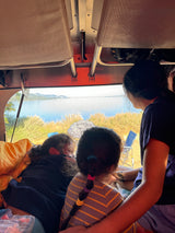 People inside an RV rental admiring a beautiful lake view, ideal for travel and camping.