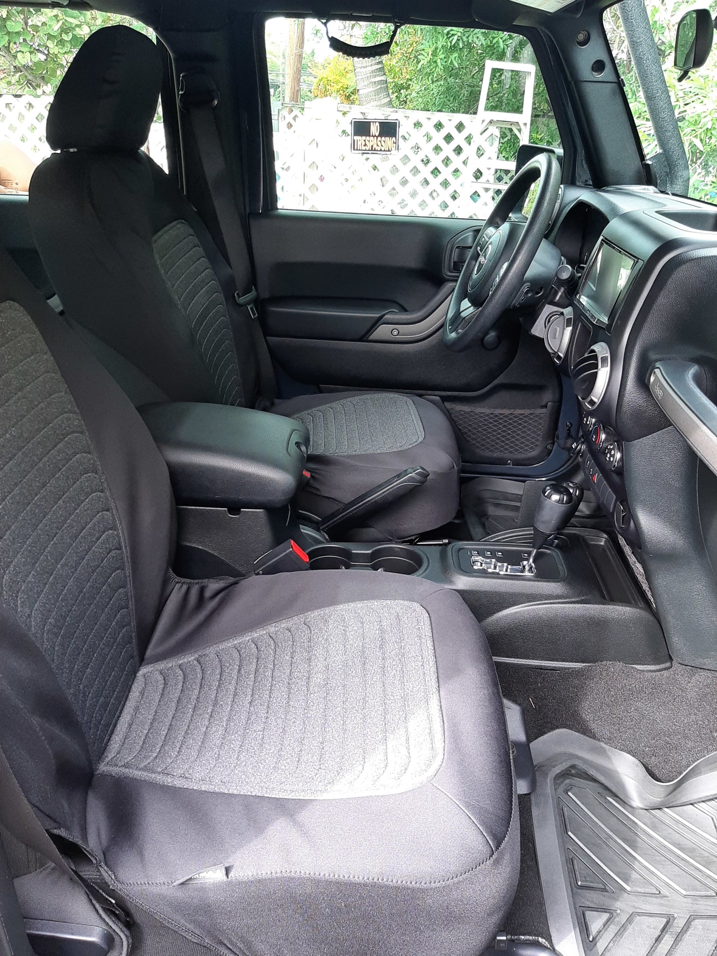 Spacious front vehicle interior, likely a Jeep, with protective seat covers and console controls, ideal for an RV rental adventure.