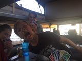 Inside an RV rental, family plays UNO. A boy makes a funny face as kids enjoy cards with an ocean view.