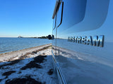 An Airstream RV rental parked on a sandy beach, reflecting the scenic bay and the Sunshine Skyway Bridge.