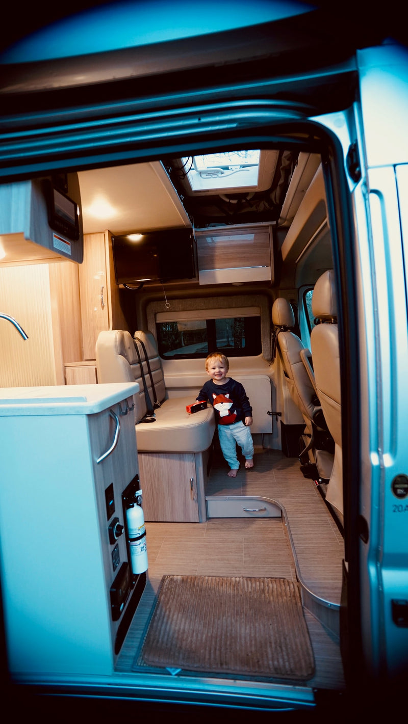 Smiling toddler in a modern RV rental camper van. View of the bright, spacious interior with kitchen & seating. — photo 3