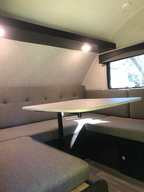 Experience comfort in this RV rental dinette featuring U-shaped bench seating, an adjustable table, and bright interior lighting.