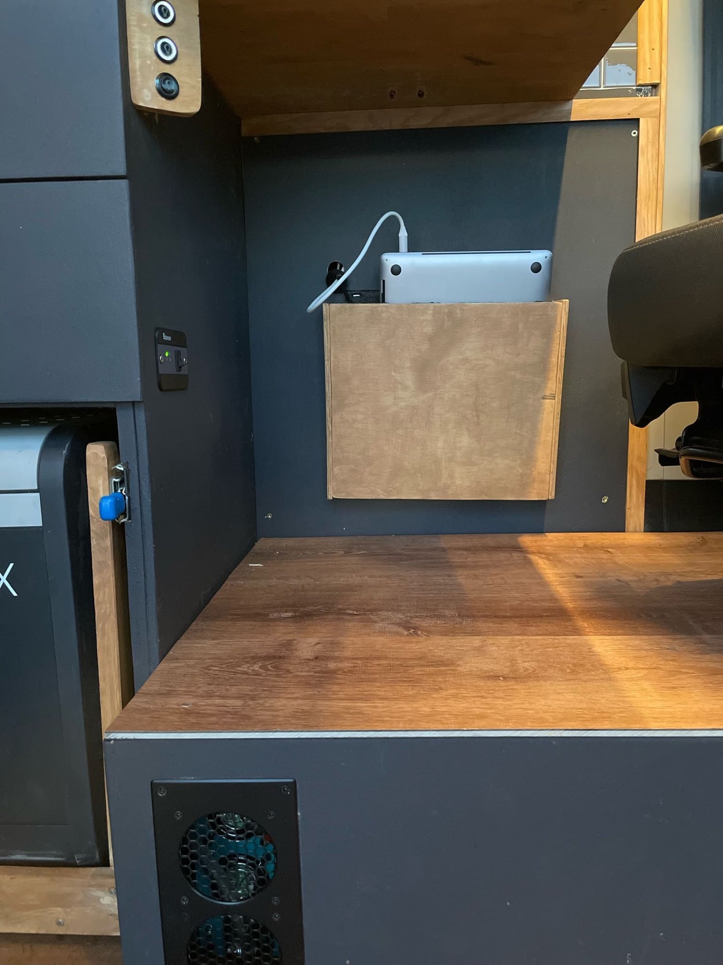 RV rental interior: organized mobile workspace featuring a laptop charging station, power outlets, a fridge, and ventilation system.