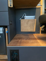 RV rental interior: organized mobile workspace featuring a laptop charging station, power outlets, a fridge, and ventilation system.