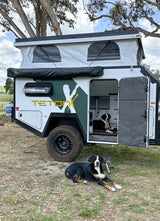 RV rental: TetonX pop-top camper trailer setup with two dogs; one inside, one outside on the grass. Great for pet travel.