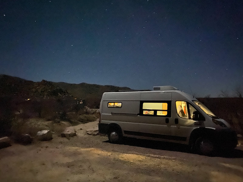 Experience van life with this RV rental! A cozy white camper van under a starry night sky, nestled against dark mountains. — photo 8