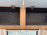RV rental interior: Open overhead storage cabinets with light wood trim and dark felt lining, perfect for organized travel.