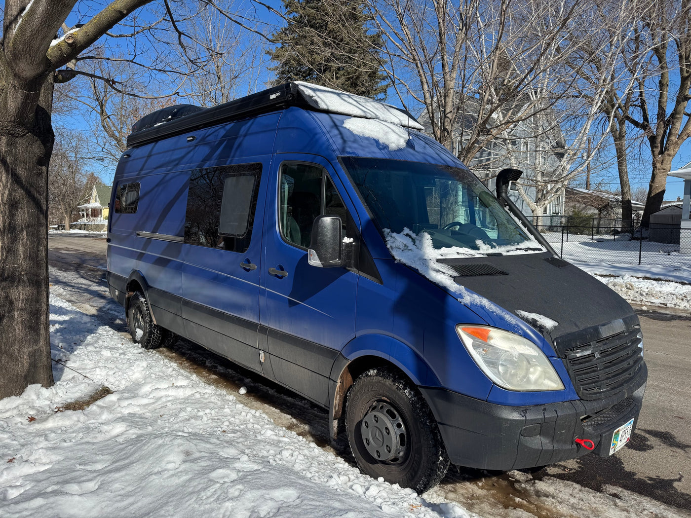 Bright blue Sprinter camper van, a perfect rv rental, parked on a snowy street under a clear winter sky. — photo 11
