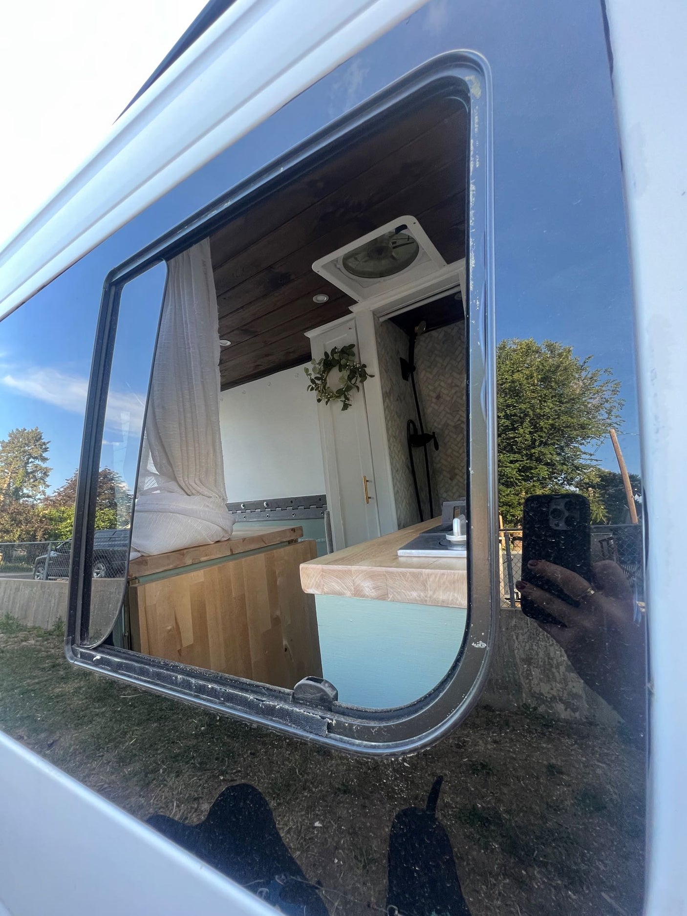 Explore this cozy RV rental's interior! Through the window, see its stylish kitchen, shower, and living area, ideal for mobile adventures.