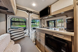 Cozy RV rental interior with a compact kitchen, comfortable seating, and TV, offering views of nature.